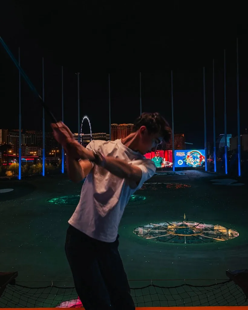 Enzo Deligny hitting golf balls at TopGolf Las Vegas